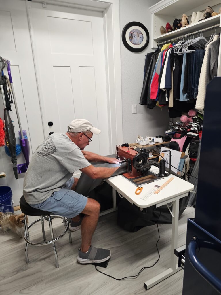 A man using a heavy-duty sewing machine in a table.